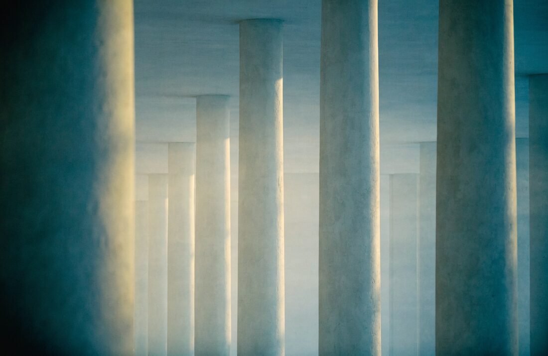 Colunata de pedra clara com luz suave, arte-conceito sobre rigor institucional e ético