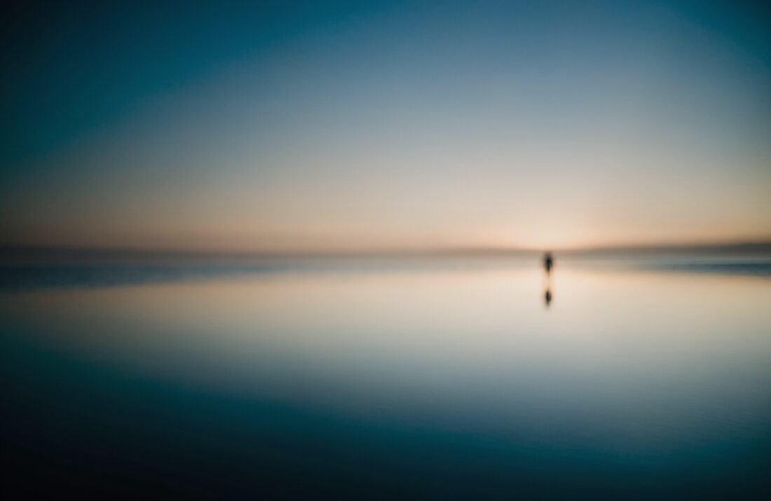 Pessoa ao amanhecer diante de água calma, arte-conceito sobre reencontrar clareza e paz